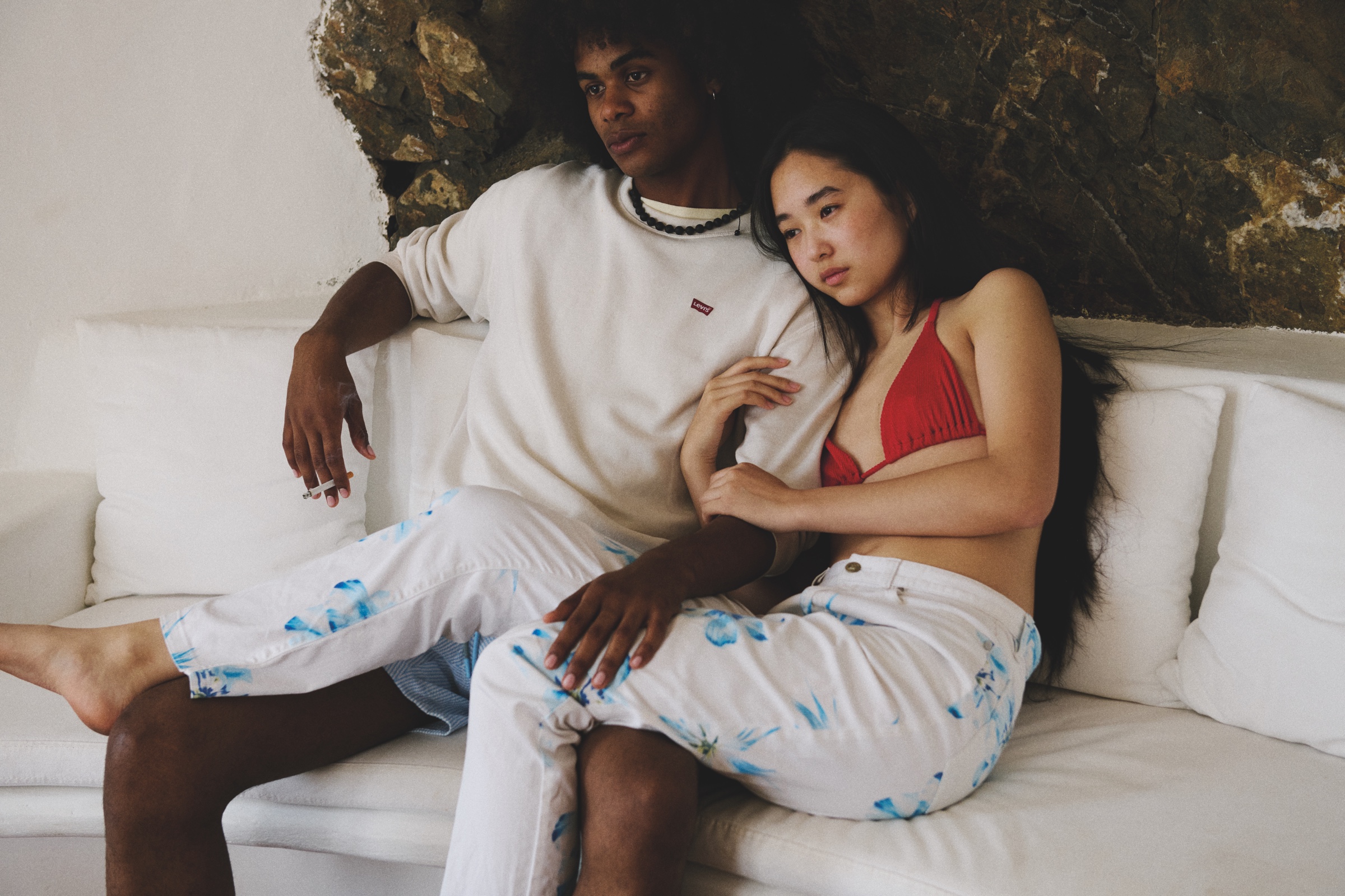 A young couple sits closely together on a white sofa.